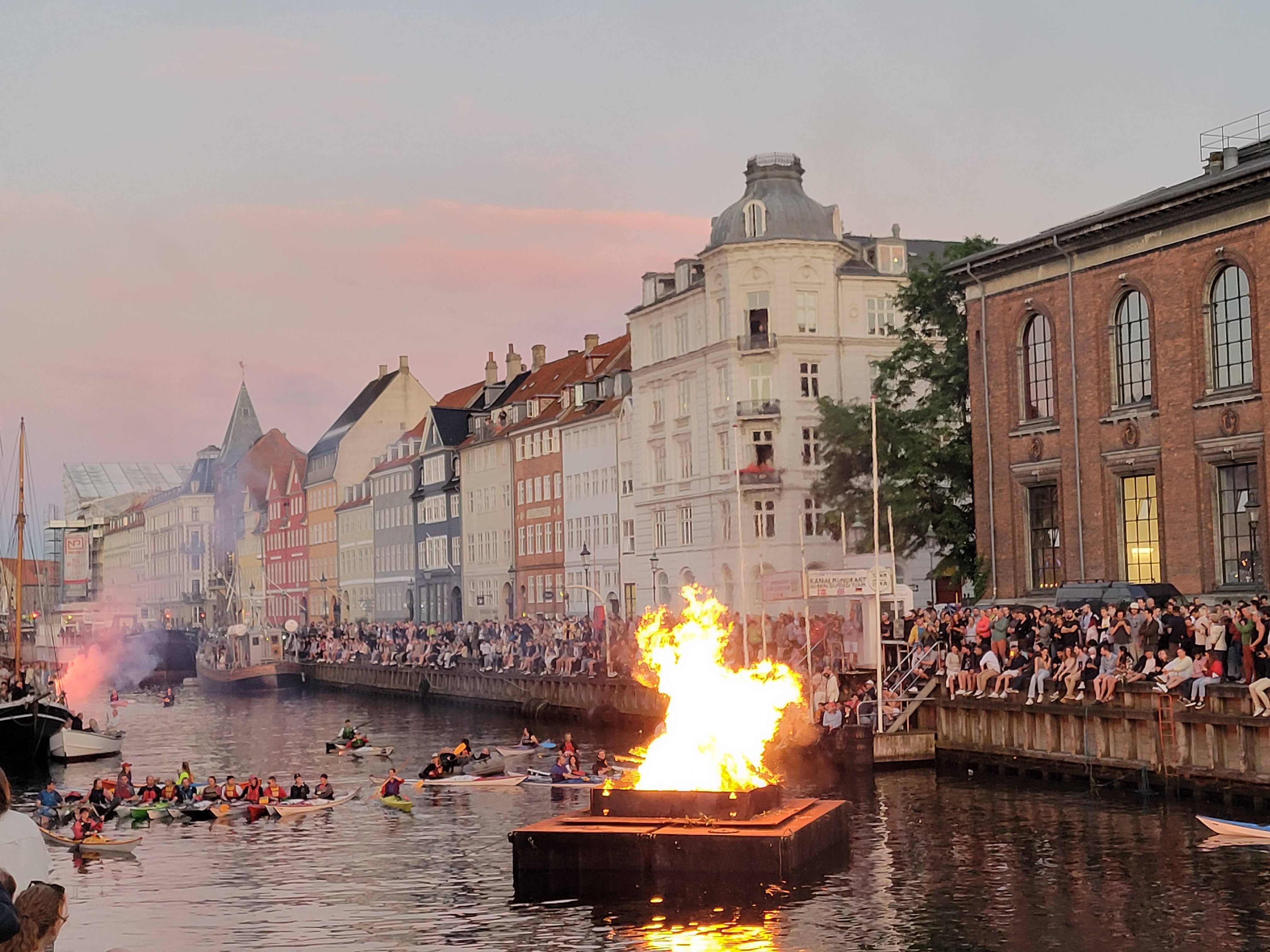 Crowds watch a witch effigy burn on a Copenhagen canal during Sankt Hans Eve