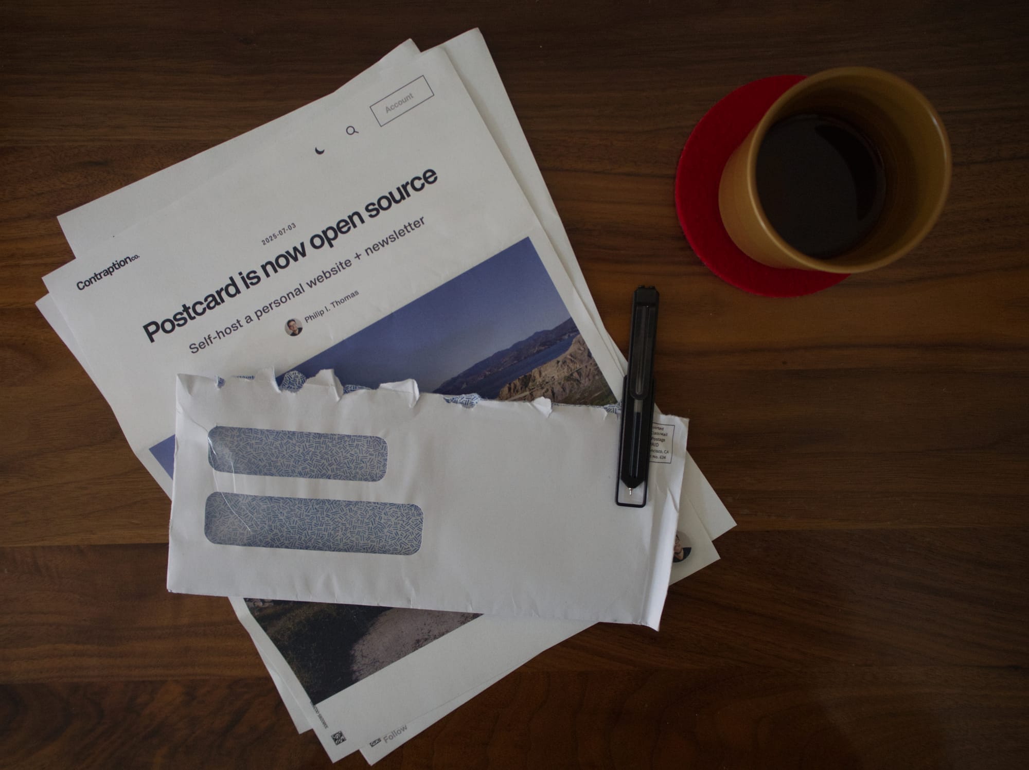 Printed newsletter pages and envelopes on a desk with coffee
