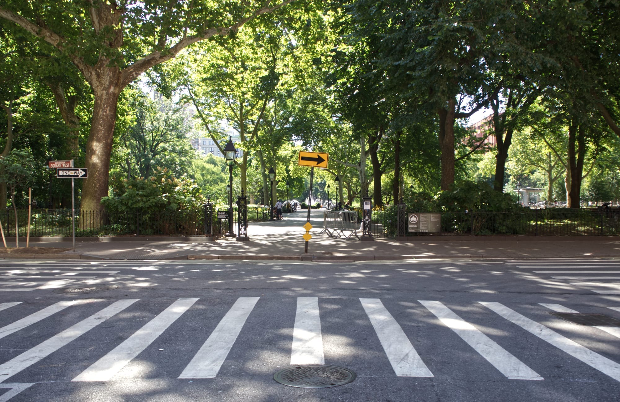 Tree-lined crosswalk at a park entrance in Manhattan