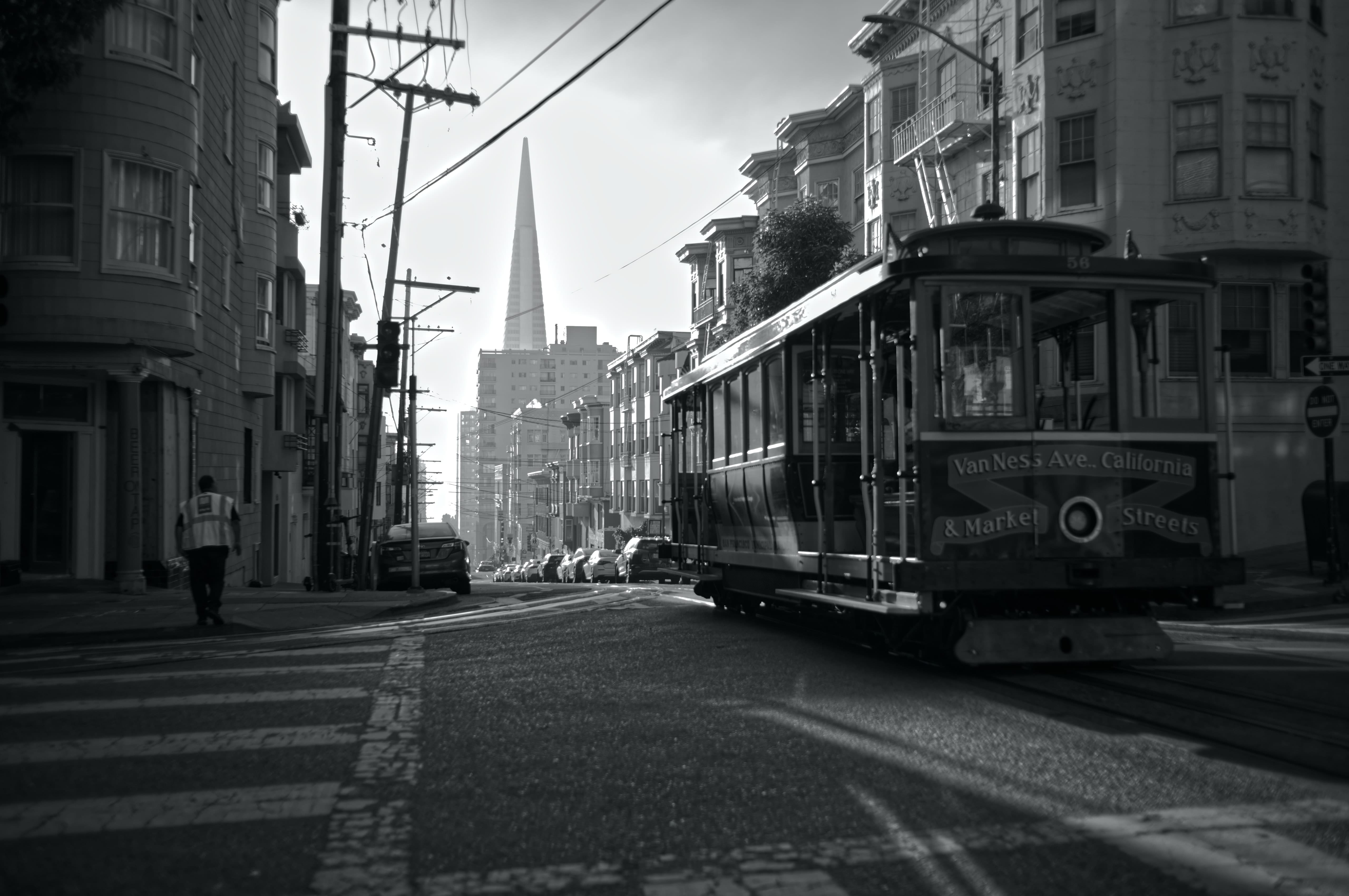 Black-and-white photograph of a cable car on a San Francisco street, with the Transamerica Pyramid in the distance