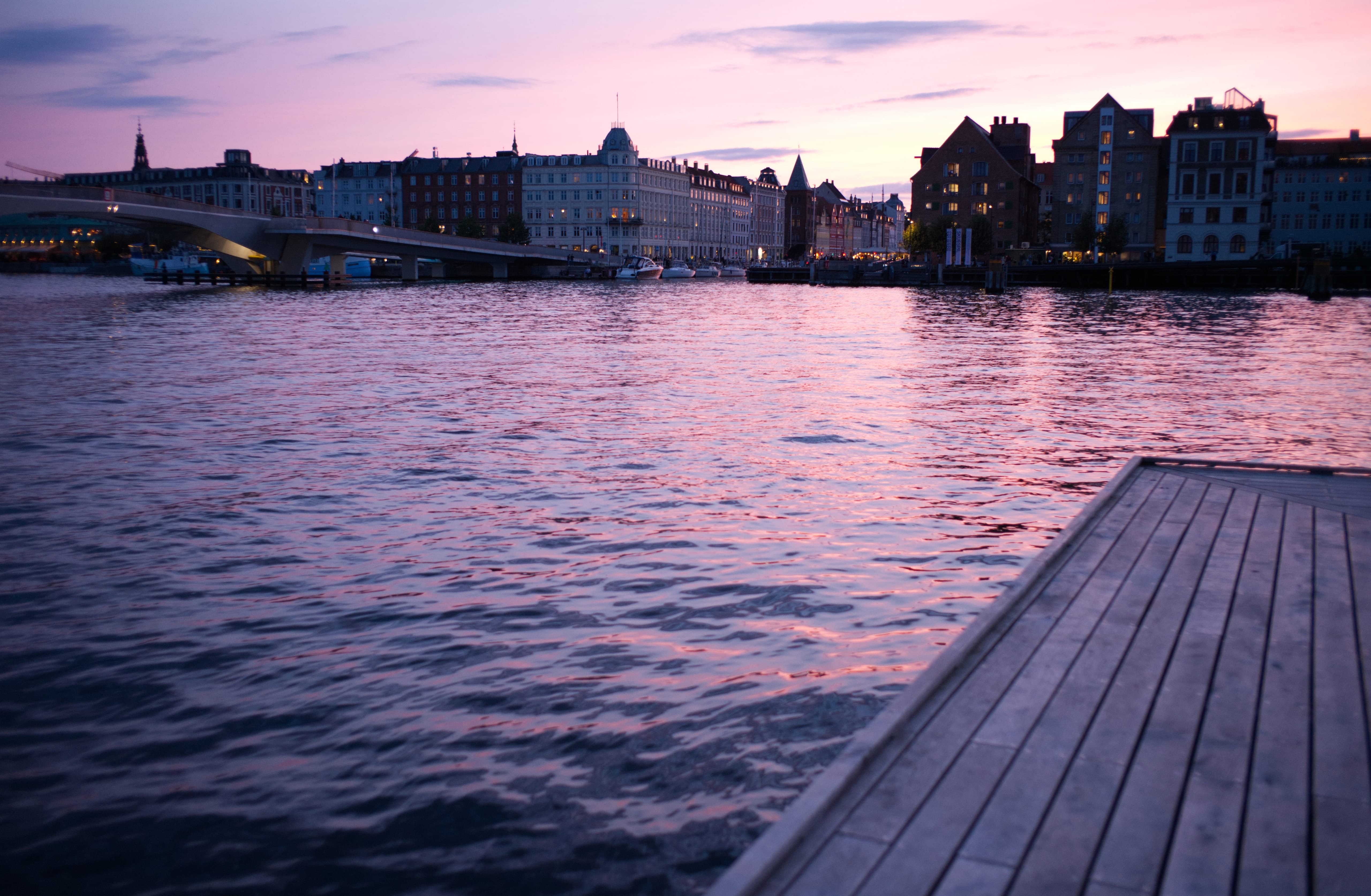 Pink sunset light reflected across Copenhagen harbor toward the city waterfront