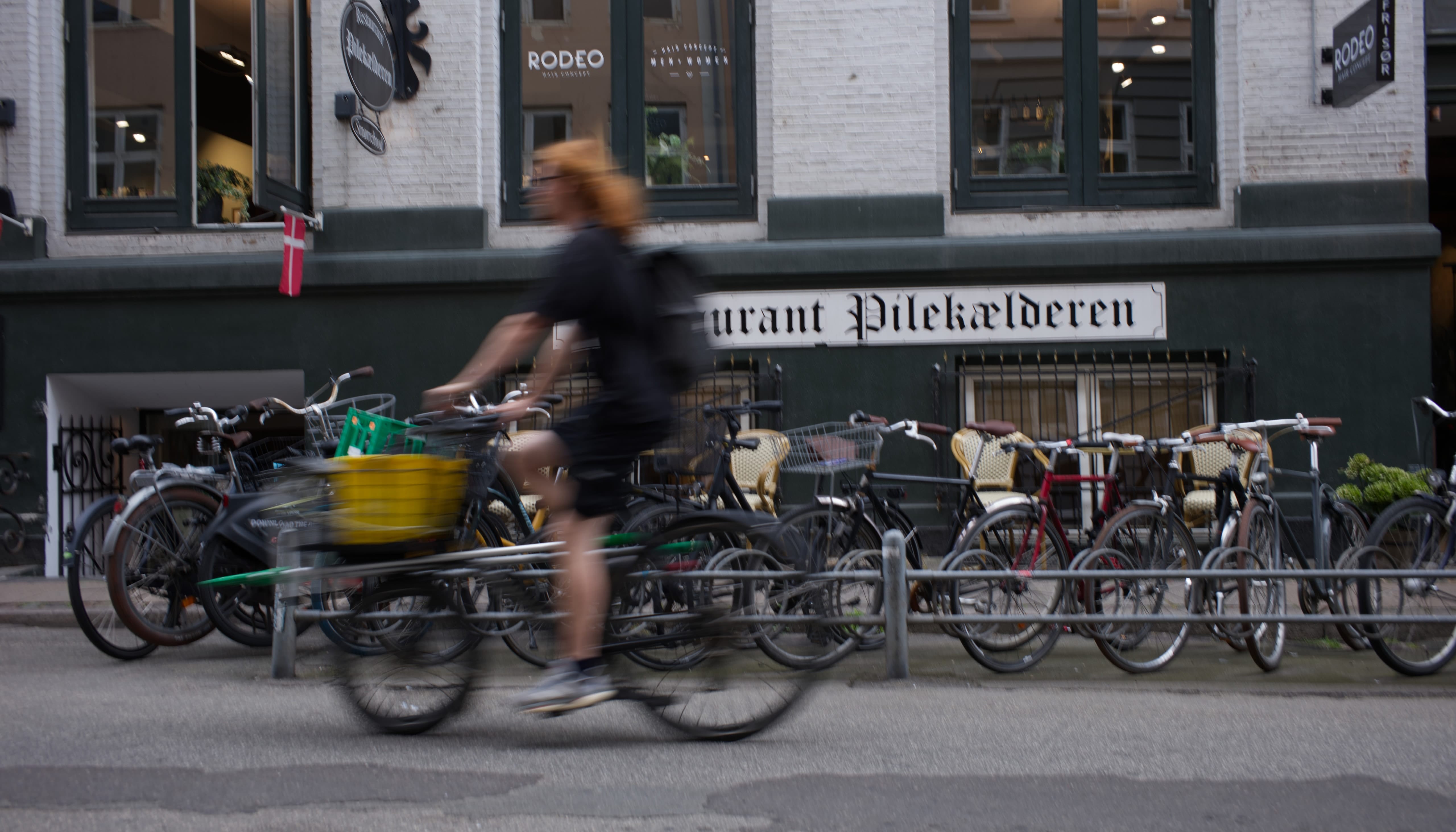 A cyclist riding past a row of parked bicycles in Copenhagen
