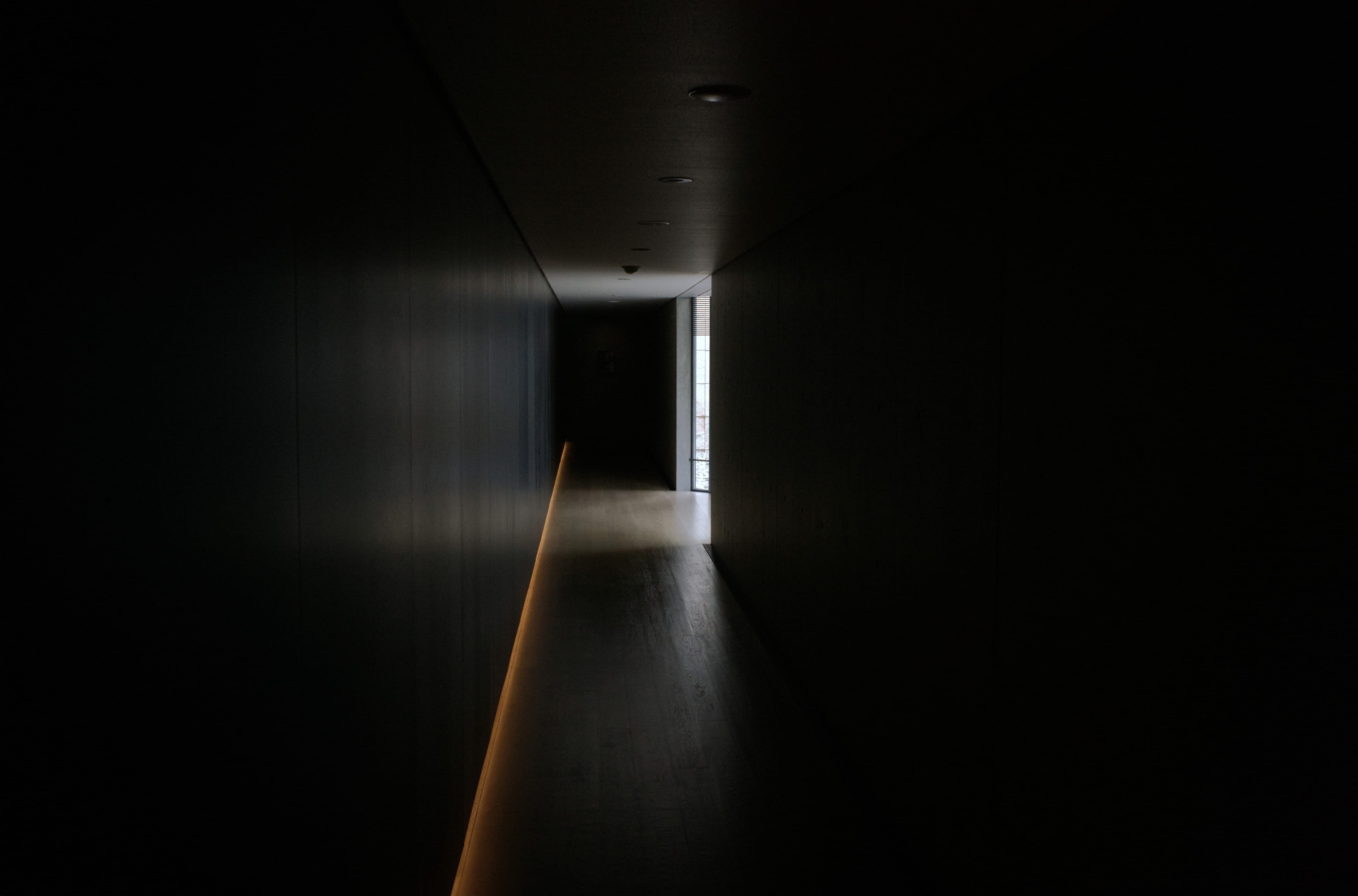 A dark hallway inside the D. T. Suzuki Museum with a narrow strip of light along the floor