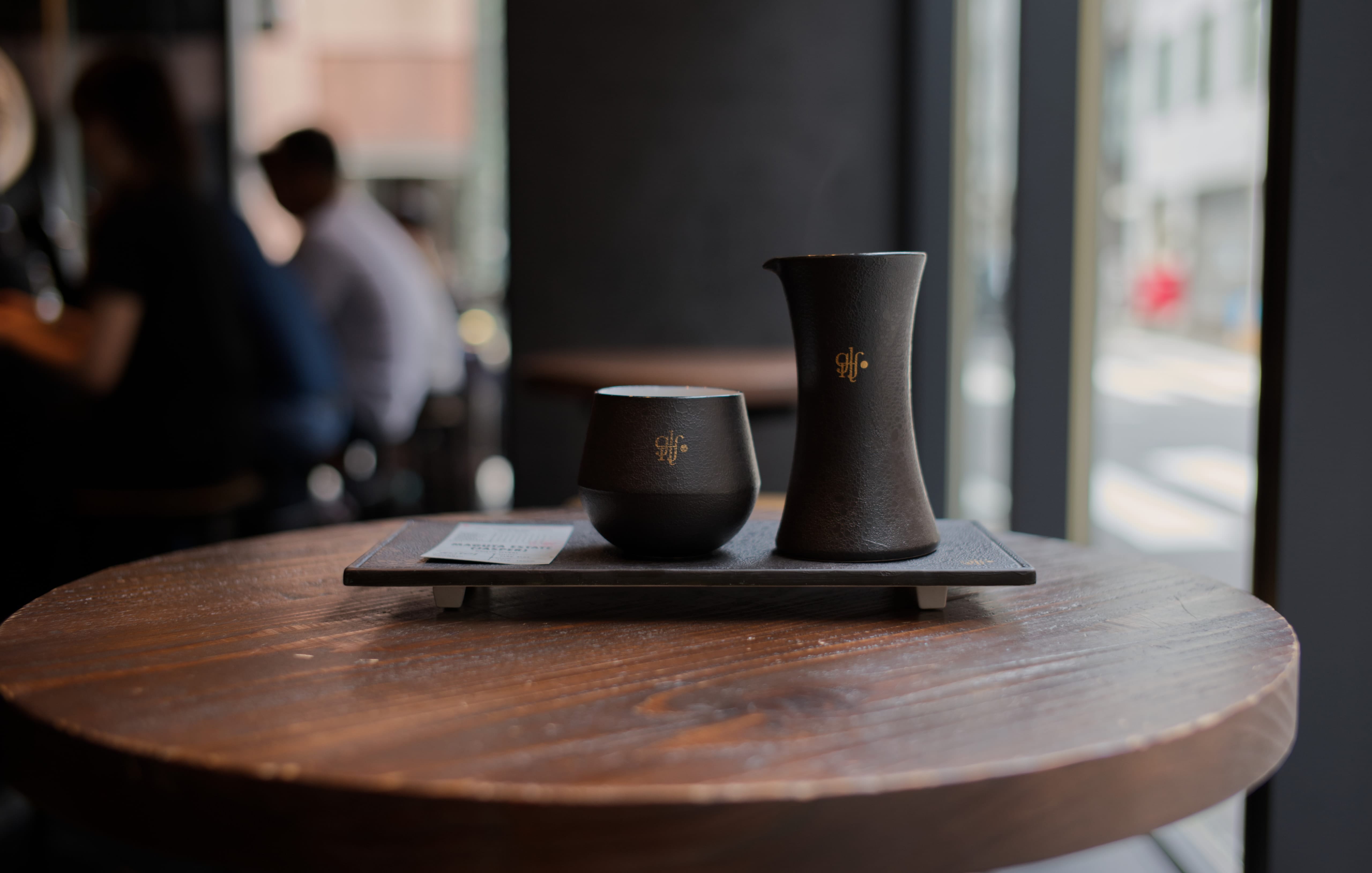 A cup and server of Geisha coffee on a wooden table at Glitch