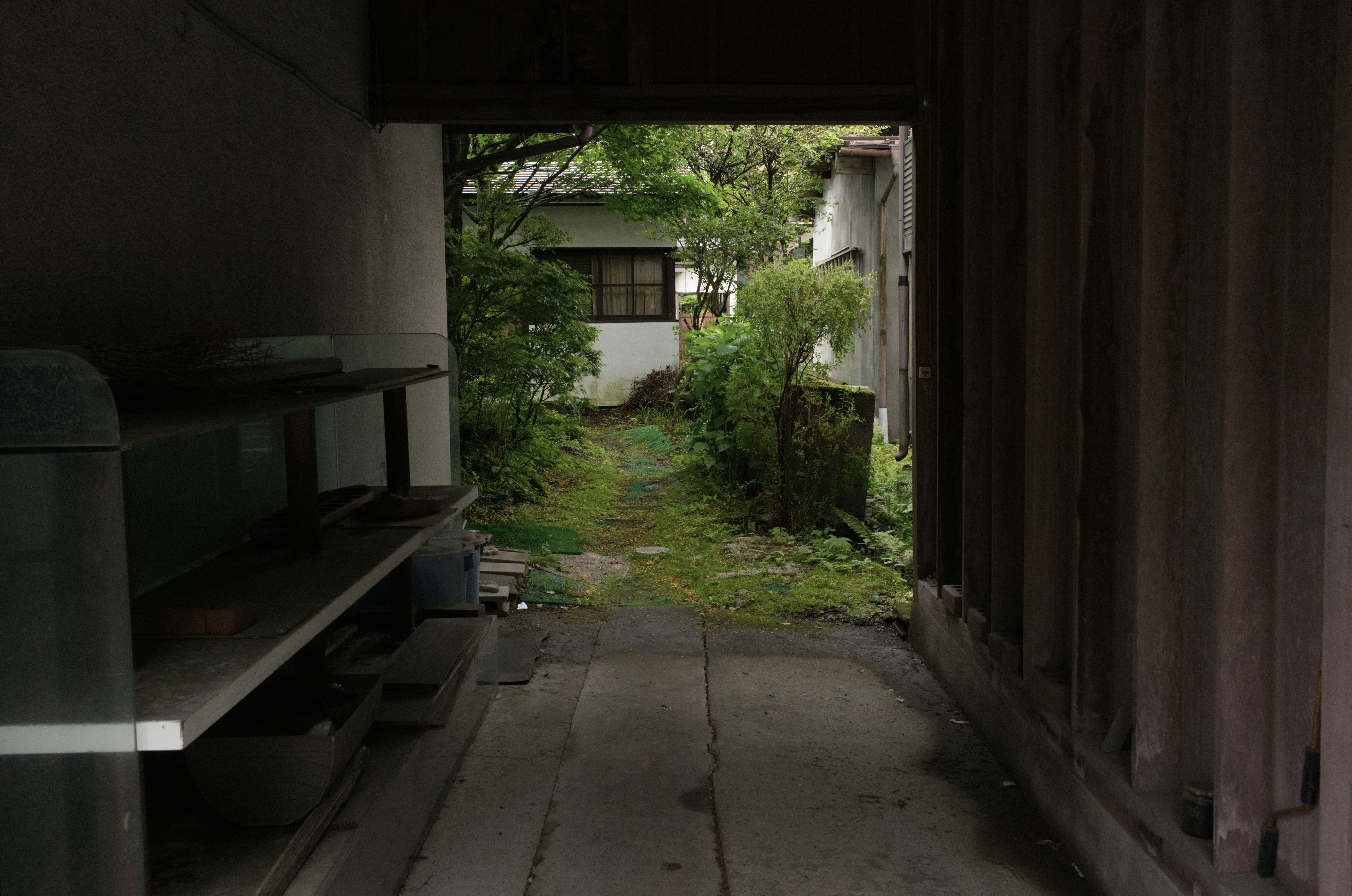 A shaded passageway looking toward a small house and garden in Karuizawa