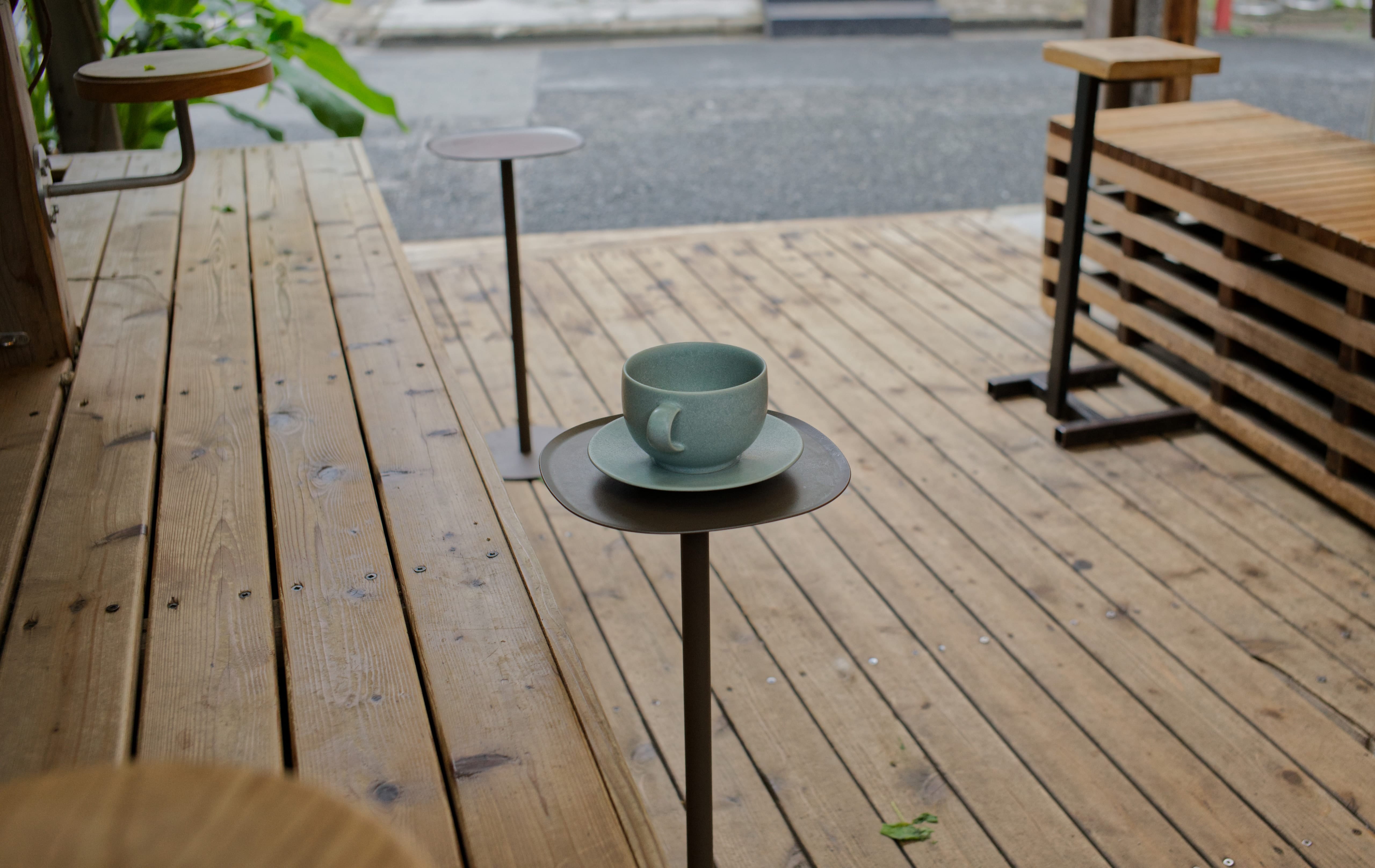 A coffee cup on a small table on the semi-outdoor wooden terrace at Onibus Coffee