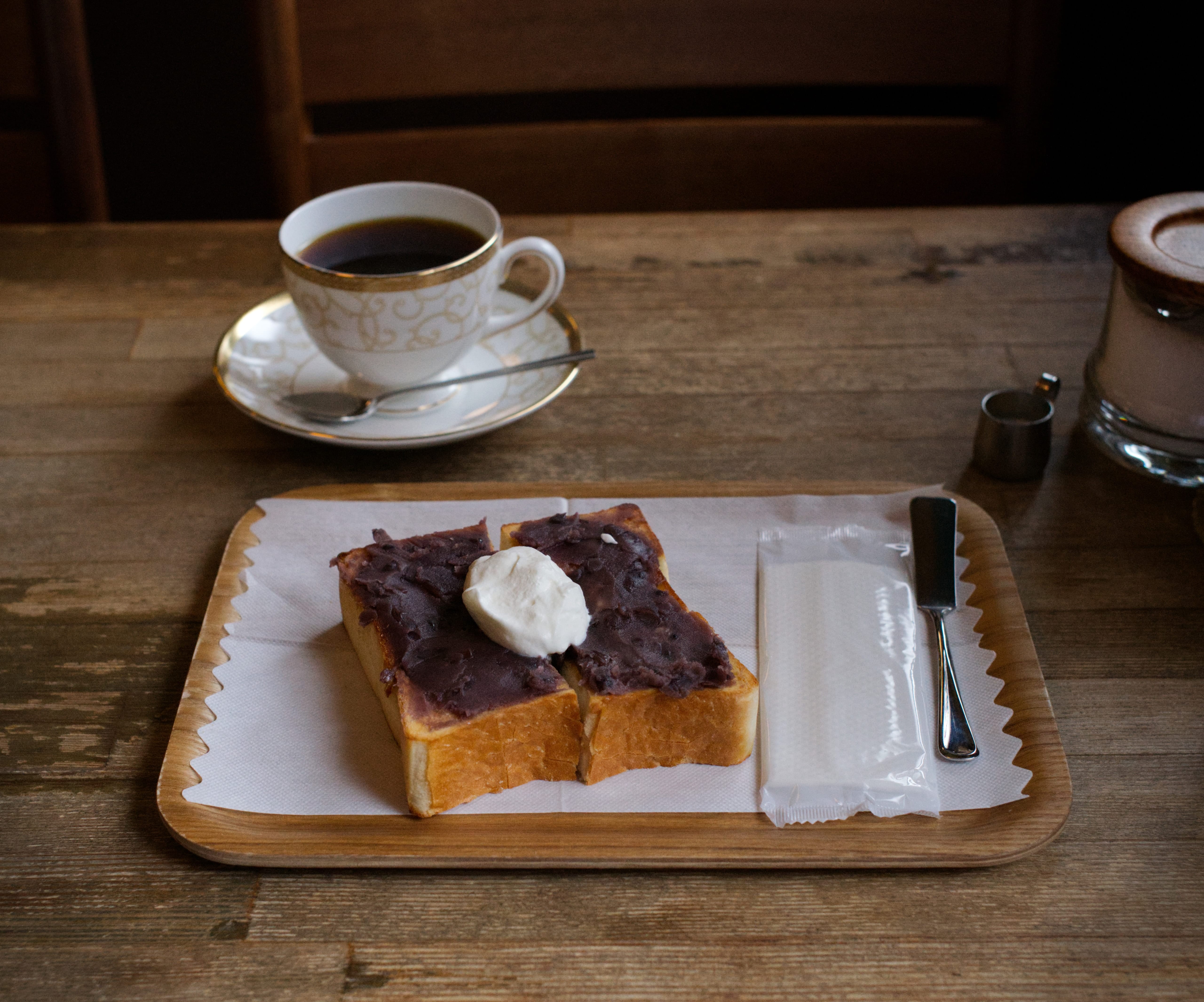 Thick toast with red bean and cream beside a cup of coffee at Higashide Coffee