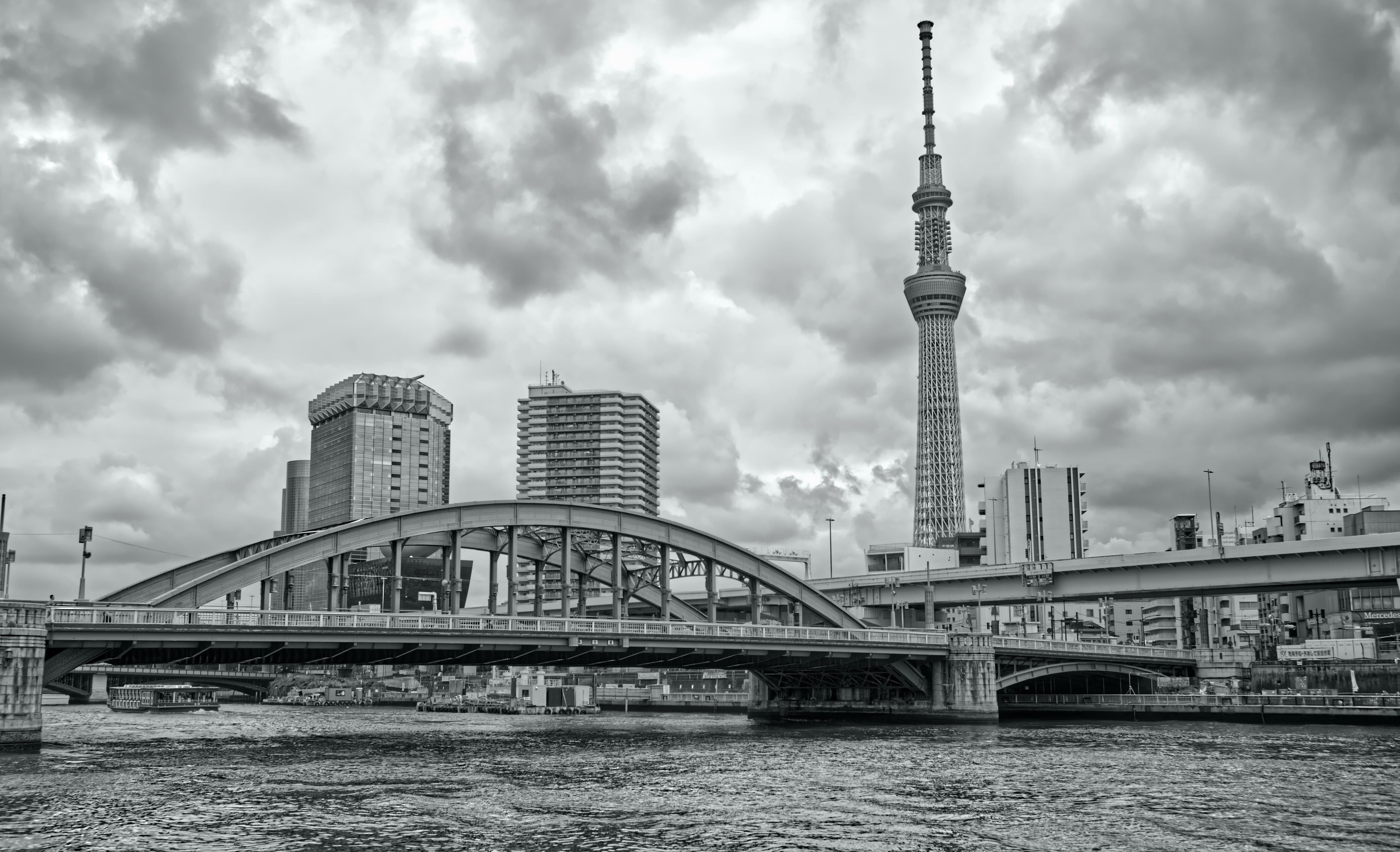 Tokyo Skytree rising over bridges and the Sumida River under heavy clouds