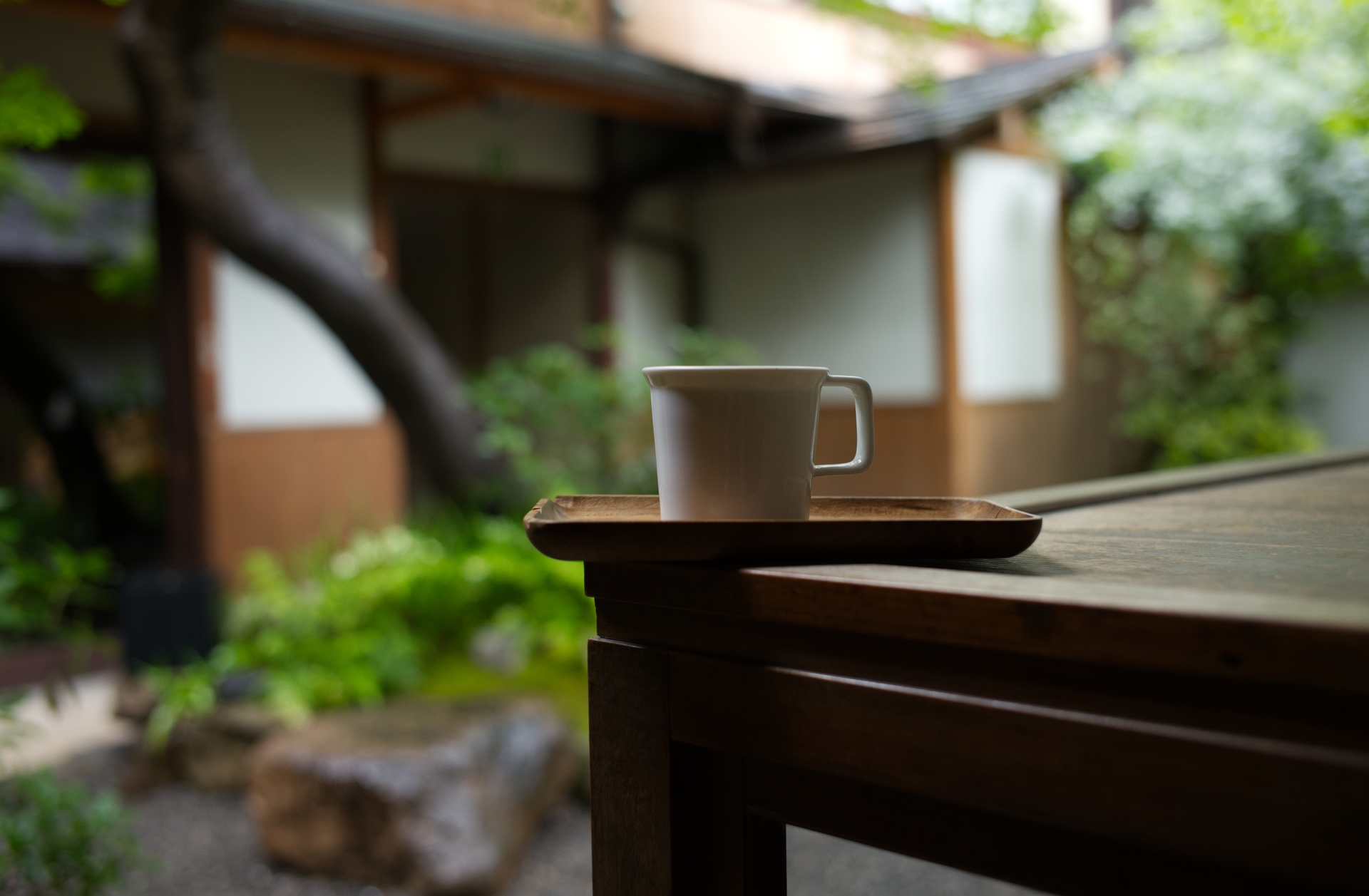 A white coffee cup on a wooden tray beside a garden at Weekenders Coffee