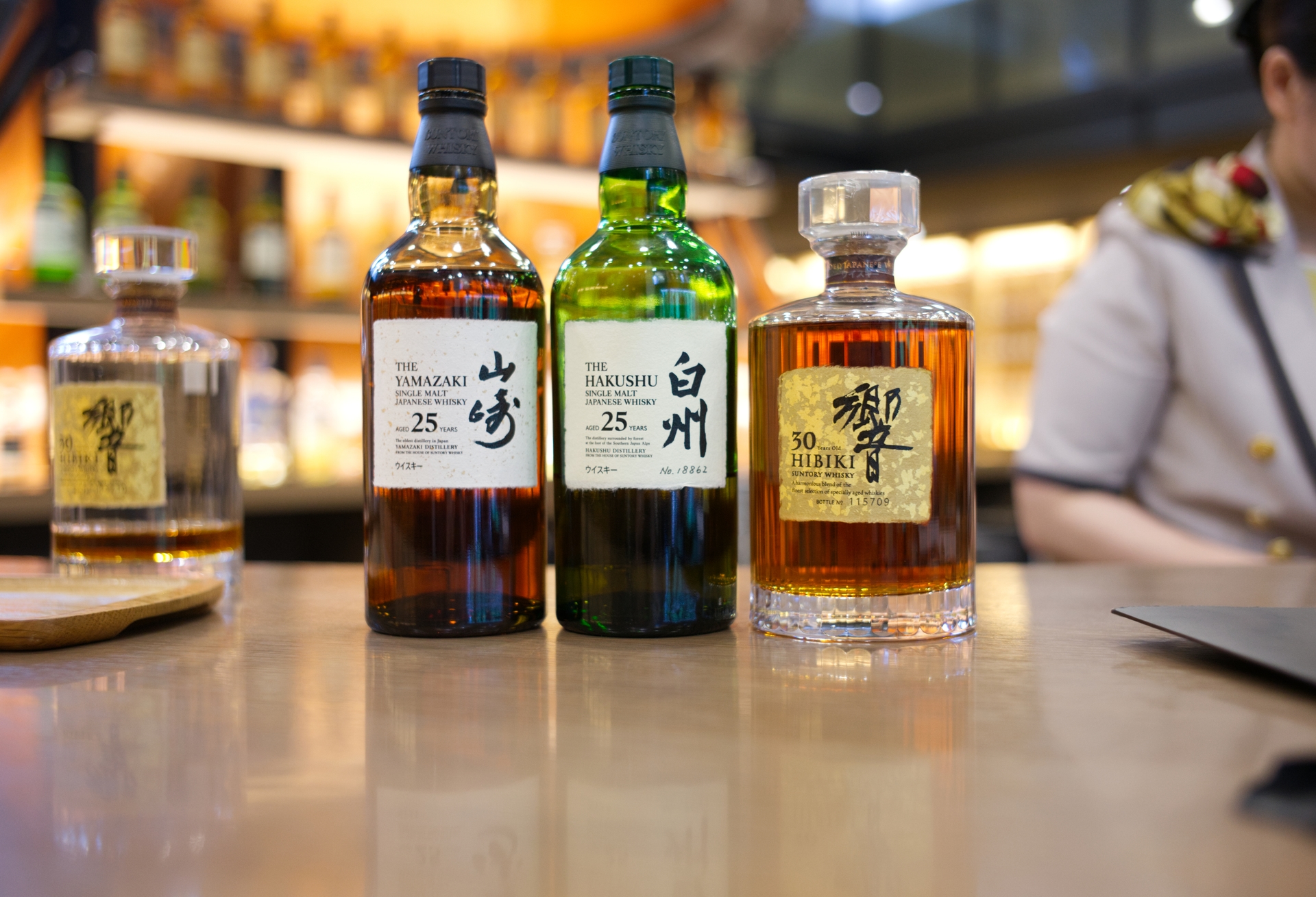 Rare Yamazaki, Hakushu, and Hibiki whisky bottles on a bar at the Suntory Yamazaki Distillery