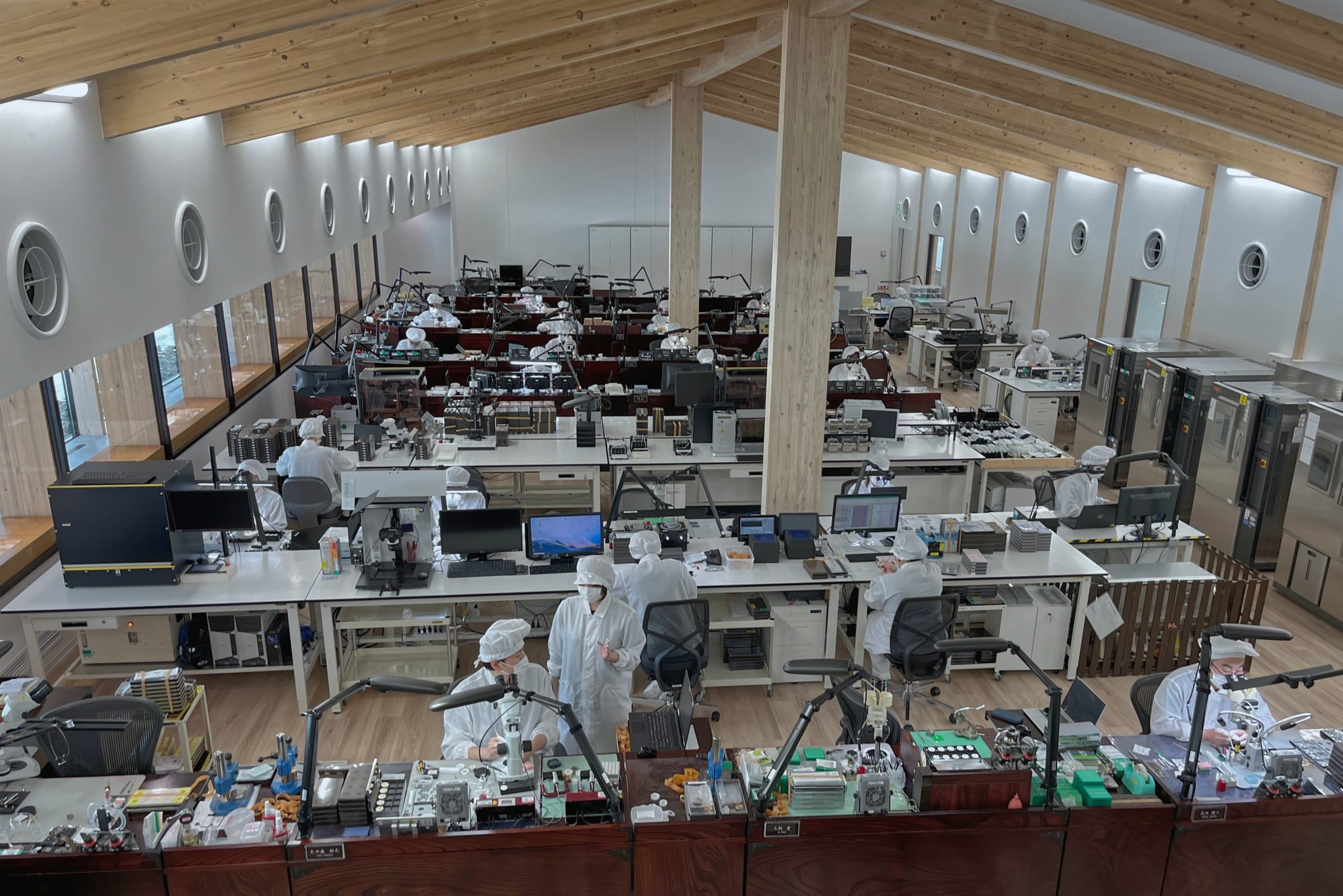 Craftspeople at wooden desks inside the clean room