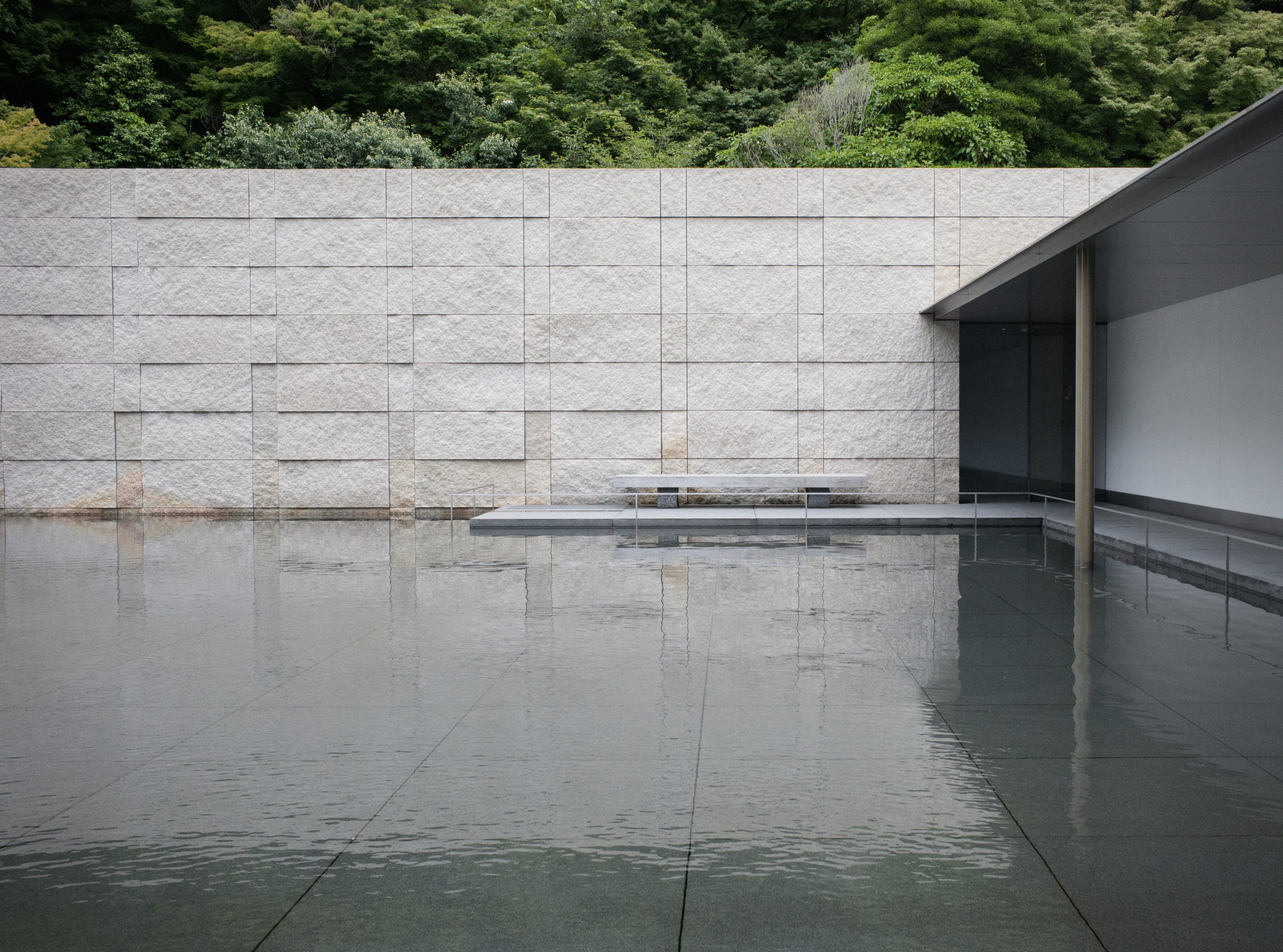 A stone bench beside the reflecting pool at the D. T. Suzuki Museum