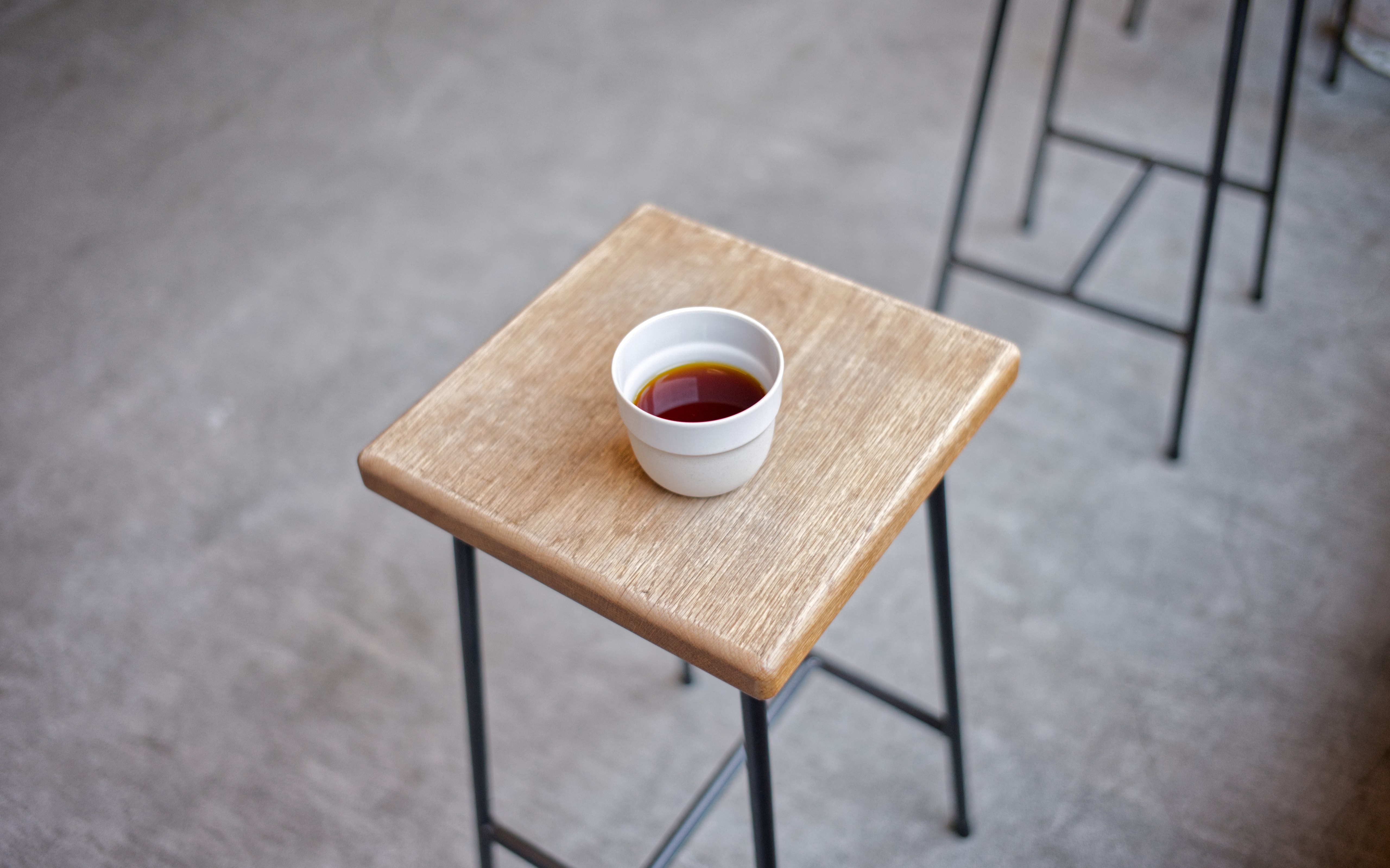 A white cup of coffee on a small wooden table at Leaves Coffee Roasters